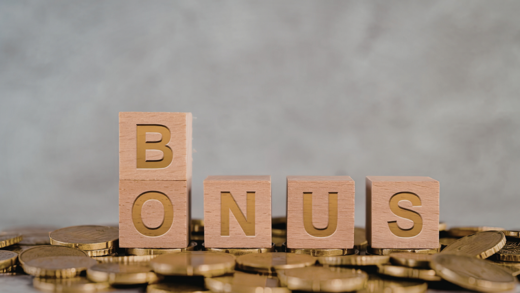 Cubes en bois formant le mot BONUS posés sur une pile de pièces de monnaie dorées.