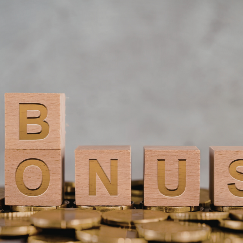 Cubes en bois formant le mot BONUS posés sur une pile de pièces de monnaie dorées.